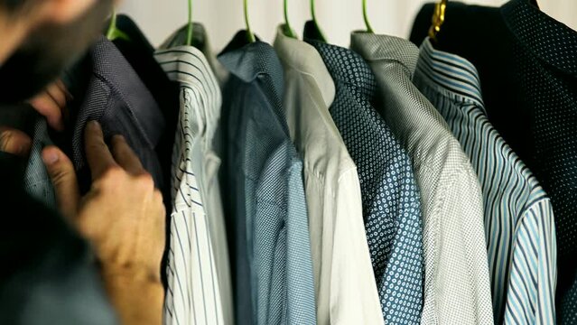 man picks out his outfit from rack of clothes