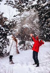 Two Children playing outdoors on winter day, laughing and throwing snow at each other.