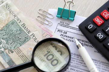 Declaration of amount of income obtained, amount of deductions made and lump sum due from recorded income, PIT-28 form on accountant table with pen and polish zloty money bills close up
