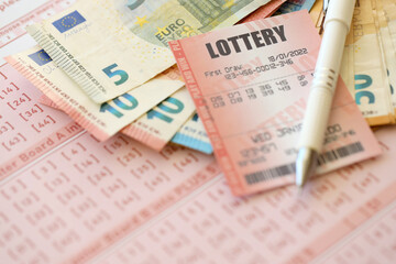 Lottery ticket and gambling receipt on table with pen and European Union euro money bills close up