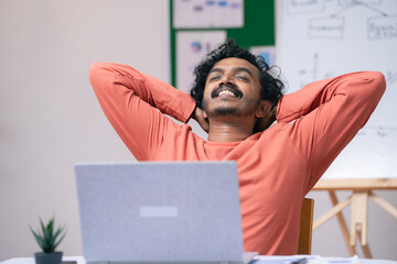 happy young man got relaxed after completing work or task at office - concept of work satisfaction,...