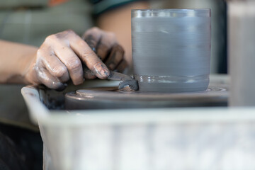 hands of a potter, creating an earthen jar on the pottery wheel