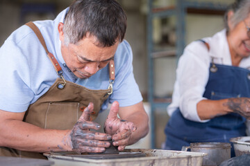 Portrait of a senior Asian couple doing activities together in the pottery workshop.
