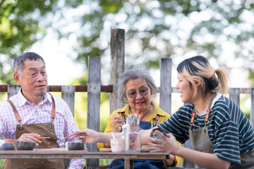 In the pottery workshop, an Asian retired couple is engaged in pottery making and clay painting activities.