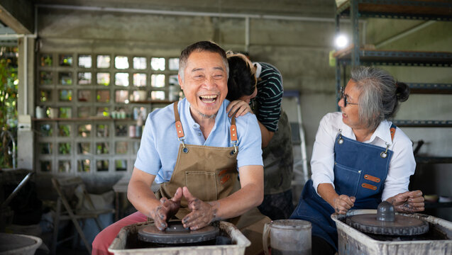 Portrait of a senior Asian couple doing activities together in the pottery workshop.