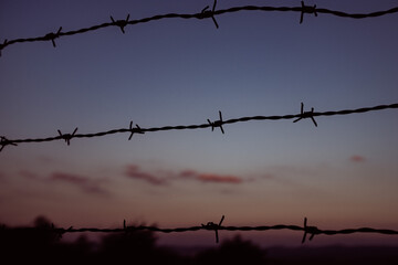 barbed wire in front of red sky during sunset
