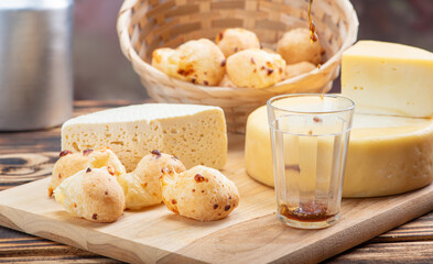 Cheese bread and cheese, a table with cheese bread and pieces of cheese and a glass of coffee on a rustic table, selective focus.