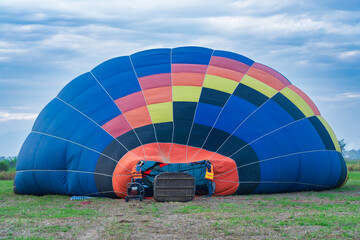 Two men prepare a balloon for flight, a basket on its side for flight.
