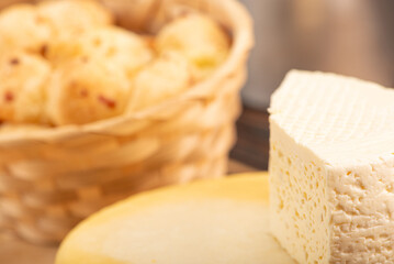 Cheese bread and cheese, a table with a basket of cheese bread and pieces of cheese on a rustic table, selective focus.