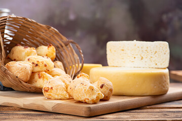 Cheese bread and cheese, a table with a basket of cheese bread and pieces of cheese on a rustic table, selective focus.