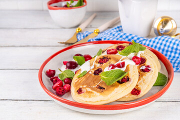 Sweet cranberry pancakes for winter breakfast or brunch. Festive Christmas, New Year breakfast dessert with vanilla creamy topping and fresh cranberries, copy space