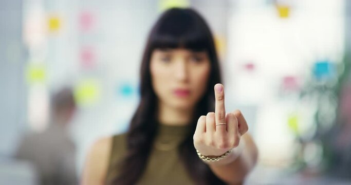 Business, face and frustrated woman with middle finger in office for inequality, anger or frustrated by compliance fail. Portrait, hands and female designer with rude emoji for corporate conflict