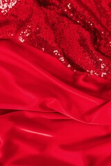 Fabric with sequins as a background. Glitter texture is the trend of the season. Sparkling color red. Abstract pattern wallpaper for the fashion industry.