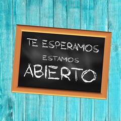 Square illustration written in Spanish We are waiting for you We're Open on a black slate with a turquoise wooden background	