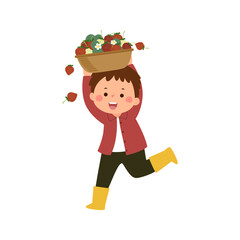 Little boy gardener carrying basket full of ripe strawberries