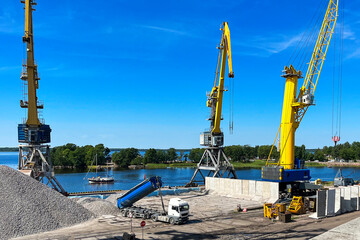 Loading and unloading operations in a commercial seaport. A port crane loads coal and crushed stone...