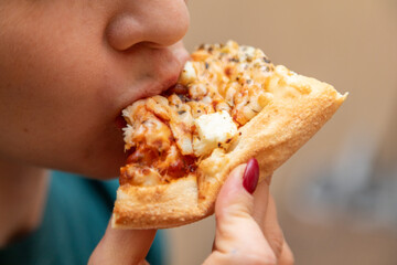 Closeup of woman eating slice of pizza