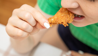 Closeup of woman in dental braces eating chicken fillet