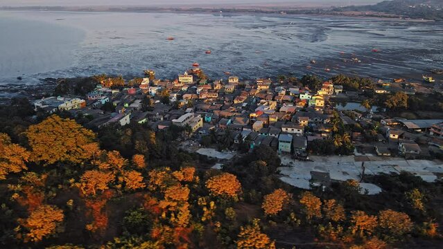An eagle-eye view of the village surrounded by palm or coconut trees and fishing boats on the beautiful coast of the Indian Ocean in the village of Mandwa near Alibuag, Maharashtra, India.