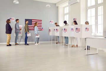 Group of multiracial voters stand in line along voting booths at polling station waiting for other...