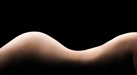The curve of the silhouette of a female body on a dark background, thin waist and perfect skin. Lateral torso and thighs
