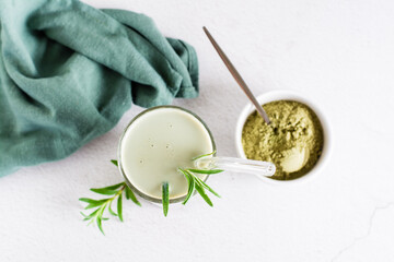Matcha latte in a glass and powder in a bowl on the table. Homemade trendy drink. Top view. Close-up