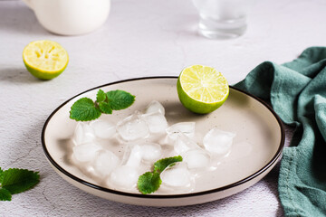 Melted ice cubes, lime and mint leaves on a plate on the table. Home made cocktails