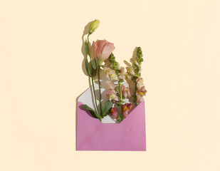 Flower bouquet in a pink envelope against the peach powder background. Minimal concept. Floral pattern. Flat lay, copy space.