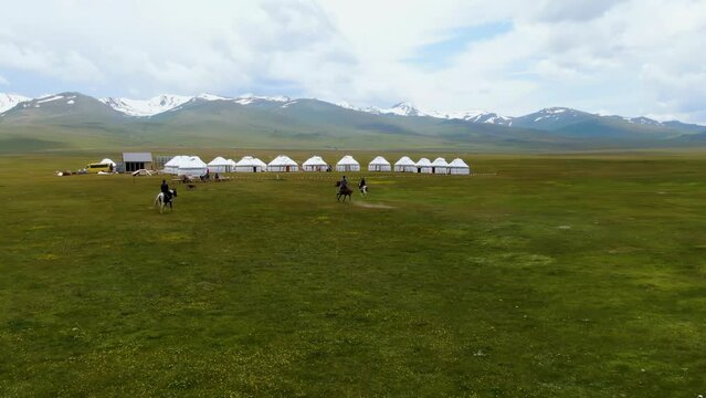 Nomadic yurt camp and snowy mountains on a meadow