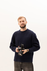 Young photographer holding professional digital camera over white background.