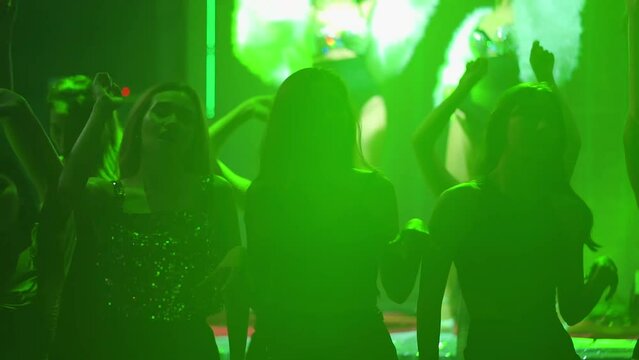 Cheerful young people dancing in night club with confetti at nightclub party. Nightlife and disco dance party concept. Fun music festival. Confetti banner background with colorful serpentine ribbons
