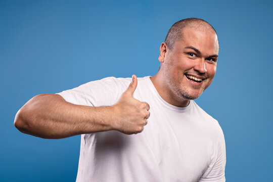 man giving a thumbs up with his right hand, raised at chest level, smiling - Powered by Adobe