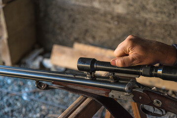 Close up for one rifle and hand on the optical sight;