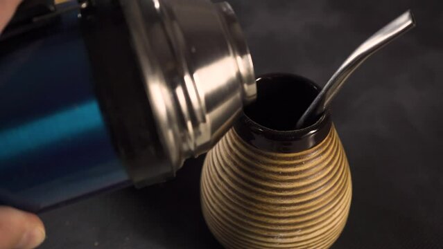 Yerba mate. Pouring hot water on matero with yerba mate