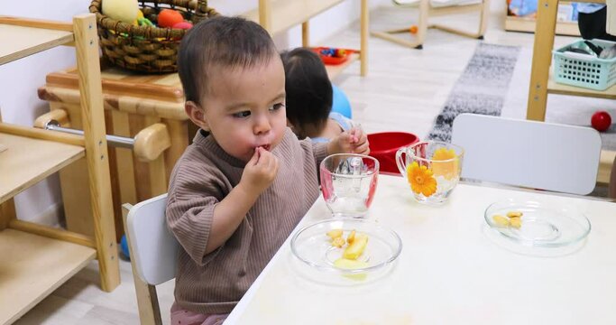 Toddler eating snacks by table