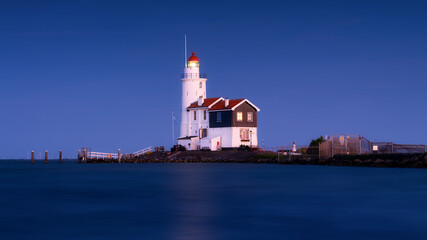 Fototapeta premium Paard van Marken, Netherlands. A lighthouse on the beach during blue hour. A landmark in maritime navigation. Long exposure. Photo for wallpaper and background.