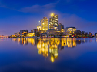 Amsterdam, Netherlands. View of the business center. Skyscrapers and reflections on the surface of the water. The famous Dutch canals. A cityscape in the evening.