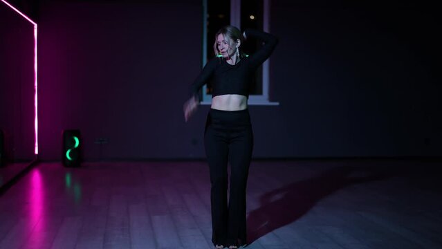 Live camera. Dancing woman in a dark choreographic hall with neon lighting. Expressive, active dance Waacking