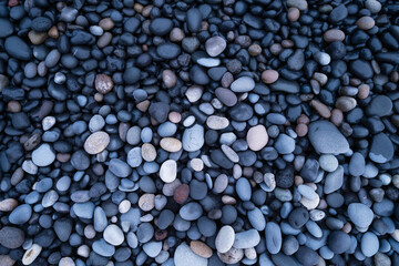 Gray pebbles as a background. Round stones on the beach. Photography for design. Image for background and wallpaper. Textures in nature.