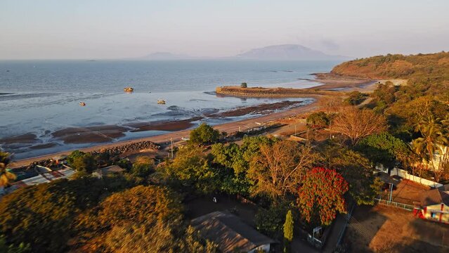 Cinematic aerial shot of a Mandwa beach near Alibuag, Maharashtra, India. The drone captures the beautiful waves crashing against the shore.