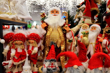 Santa Clause and Christmas dolls near Christmas tree, on store window. Beautiful favorite toys for New Year. Christmas winter shop shopping - obrazy, fototapety, plakaty