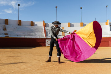 Hispanic matador dancing on sandy arena
