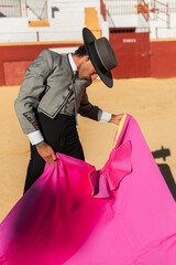 Hispanic matador dancing on sandy arena