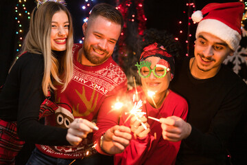 Obraz na płótnie Canvas Group of four friends celebrates New Year with sparkles