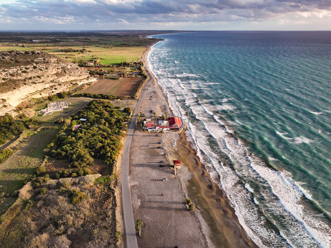 Sunset over Cyprus Kurion Beach, where golden hues dance on the serene Mediterranean waters, casting a tranquil glow. The sun kisses the horizon, painting the sky with warm shades of orange and purple