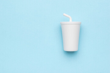 A white drink glass with a straw on a blue background.