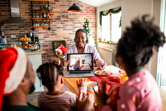 Mother showing video call with grandparents to children at home