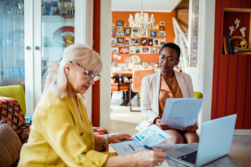 Senior woman going over documents with financial advisor at home