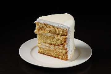 A piece of white cake with marzipan under dark lighting. Close-up