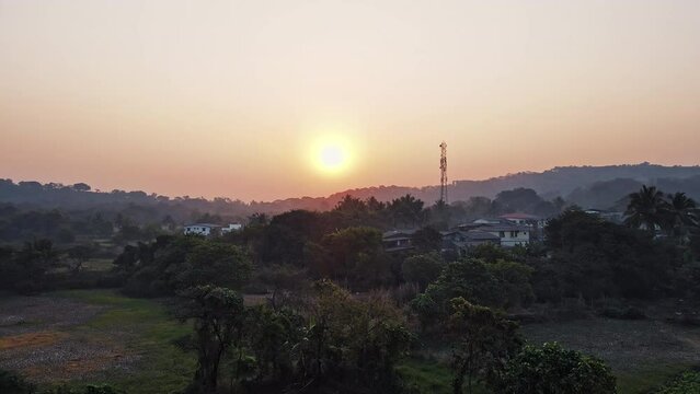 An aerial view of Mandwa Village at sunrise showcases houses surrounded by coconut trees that enhance the village's natural beauty.